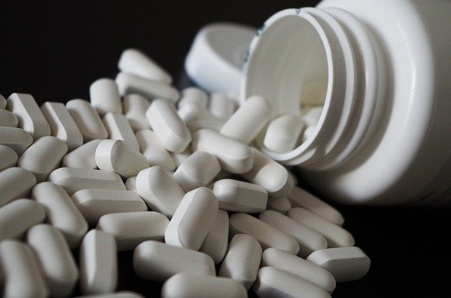převržená lékovka s bílými tabletami